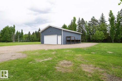 Detached outbuilding with blue siding, a white garage door, and a separate service door - 209 5128 Highway 18, Rural Barrhead County, AB 