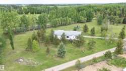 Spacious rural property featuring a white exterior home with a gray shingle roof - 
