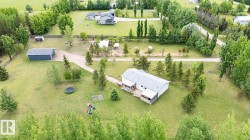 Sprawling property featuring a detached garage, gravel driveway, and multiple mature trees - 