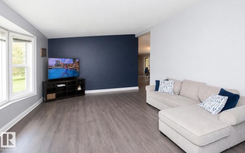 Spacious living area featuring wood-finish flooring and a neutral color palette - 209 5128 Highway 18, Rural Barrhead County, AB 