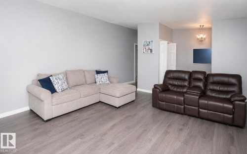 Open-concept living space with light gray walls and wood-finish flooring - 209 5128 Highway 18, Rural Barrhead County, AB 