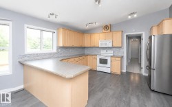 Kitchen featuring light wood cabinetry, a U-shaped countertop with a breakfast bar, white appliances, a mosaic tile backsplash, and wood-finish flooring - 