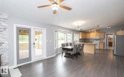 Open-concept living space featuring wood-finish flooring, a kitchen with light wood cabinetry, a central island, and white appliances - 