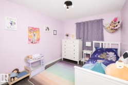 Interior room featuring light purple wall paint, dark wood-finish flooring, a white trim, a semi-flush ceiling light fixture, and a window with purple curtains - 