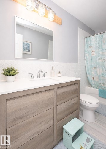 Modern bathroom featuring a wood-finish vanity with a white countertop and integrated sink - 209 5128 Highway 18, Rural Barrhead County, AB 