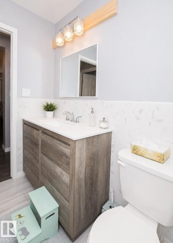 Bathroom vanity with a white countertop and integrated sink, chrome faucet, and wood-finish cabinetry - 209 5128 Highway 18, Rural Barrhead County, AB 