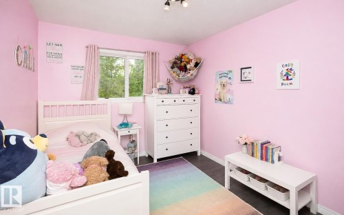 Bedroom featuring a window with exterior views, dark wood-finish flooring, and track lighting - 209 5128 Highway 18, Rural Barrhead County, AB 