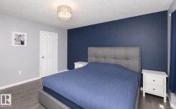 Bedroom featuring an accent wall, gray walls, wood-finish flooring, and a crystal chandelier - 