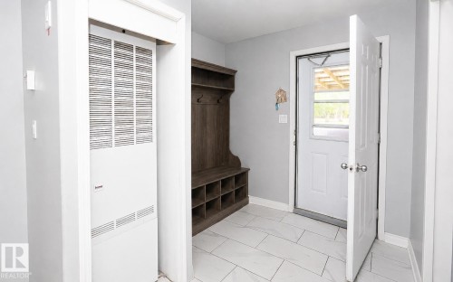 Entryway featuring light gray wall paint, white trim, and rectangular tile flooring - 209 5128 Highway 18, Rural Barrhead County, AB 