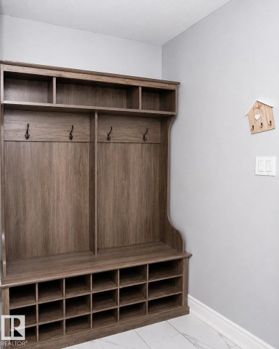 Built-in wood-finish hall tree featuring coat hooks, upper storage cubbies, bench seating, and lower shoe cubbies - 209 5128 Highway 18, Rural Barrhead County, AB 