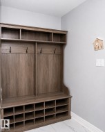 Built-in wood-finish hall tree featuring coat hooks, upper storage cubbies, bench seating, and lower shoe cubbies - 