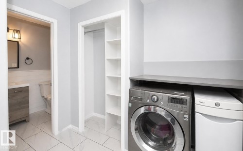 Dedicated laundry area featuring a countertop surface, integrated shelving, and white tile flooring - 209 5128 Highway 18, Rural Barrhead County, AB 