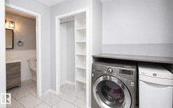 Dedicated laundry area featuring a countertop surface, integrated shelving, and white tile flooring - 
