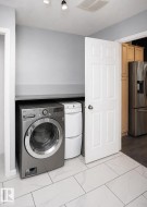 Dedicated laundry area featuring a front-load washer, stacked dryer unit, and overhead shelving - 