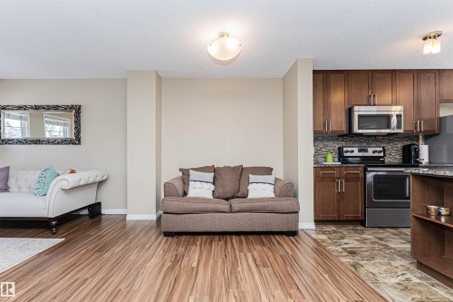 Open-concept living area featuring wood-finish flooring, neutral wall tones, and a modern ceiling light fixture - 31 4029 Orchards Drive, Edmonton, AB 