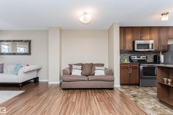 Open-concept living area featuring wood-finish flooring, neutral wall tones, and a modern ceiling light fixture - 