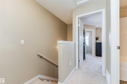 Upper-level landing featuring neutral paint, white trim, and carpeted flooring - 