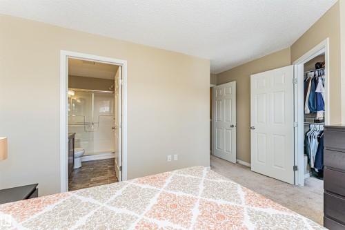 Bedroom featuring neutral tone walls, textured ceiling, carpet flooring, and a walk-in closet with an open doorway - 31 4029 Orchards Drive, Edmonton, AB 