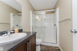 Bathroom featuring a glass-enclosed shower, dark wood-finish vanity with a light-toned countertop, and a white oval undermount sink with a chrome faucet - 