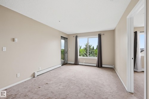 Spacious room featuring neutral carpeting and light-toned walls - 304 11804 22 Avenue, Edmonton, AB 