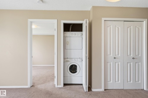 Integrated stackable washer and dryer unit, neutral tone carpeting, and classic white paneled doors - 304 11804 22 Avenue, Edmonton, AB 