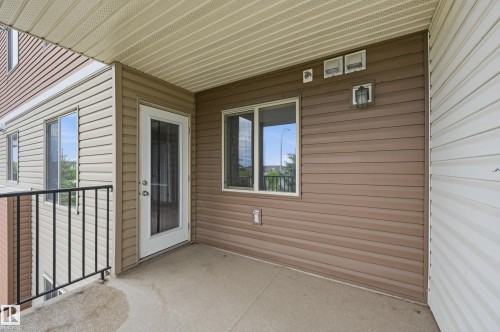 Outdoor balcony featuring concrete flooring, black metal railing, and a glass-paneled door - 304 11804 22 Avenue, Edmonton, AB 