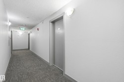 Hallway featuring gray patterned carpet, white walls, flush-mount lighting fixtures, and a textured ceiling - 