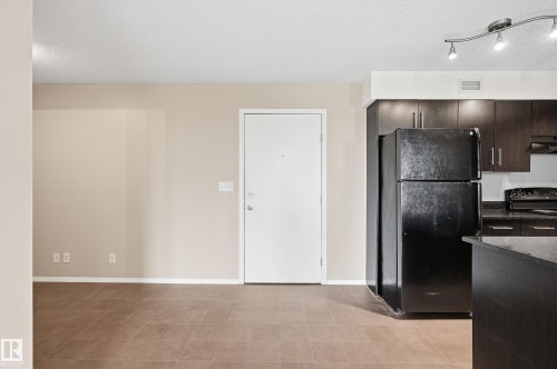 Kitchen area featuring dark wood-finish cabinetry, black appliances, and dark countertops - 304 11804 22 Avenue, Edmonton, AB 
