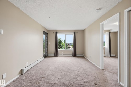 Spacious room featuring neutral carpeting and light beige wall tones - 304 11804 22 Avenue, Edmonton, AB 
