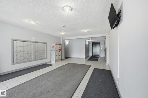 Lobby area featuring built-in mailboxes, secure package lockers, and tile flooring - 304 11804 22 Avenue, Edmonton, AB 