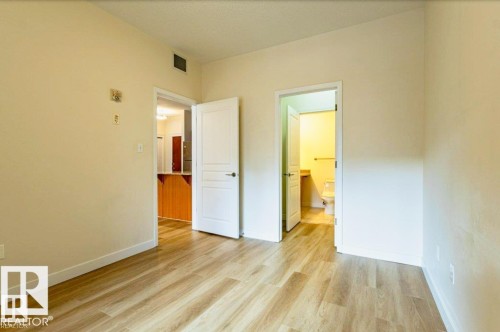 Light wood-finish flooring throughout, complemented by neutral wall tones and white baseboards - 409 10333 112 Street, Edmonton, AB 