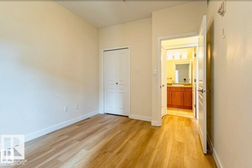 Room featuring wood-finish flooring, light-toned walls, and white baseboards - 409 10333 112 Street, Edmonton, AB 