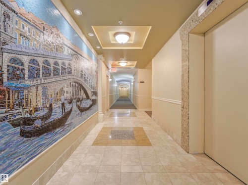 Hallway featuring a detailed mosaic art wall, recessed ceiling lighting, decorative ceiling soffits, tile flooring, and an elevator access point - 409 10333 112 Street, Edmonton, AB 