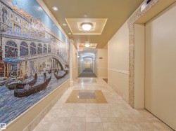 Hallway featuring a detailed mosaic art wall, recessed ceiling lighting, decorative ceiling soffits, tile flooring, and an elevator access point - 