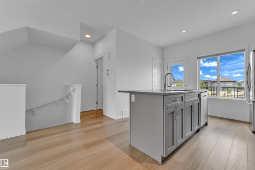 Contemporary kitchen island with grey cabinetry, a stainless steel faucet, and an integrated sink - 1534 157 Street, Edmonton, AB 