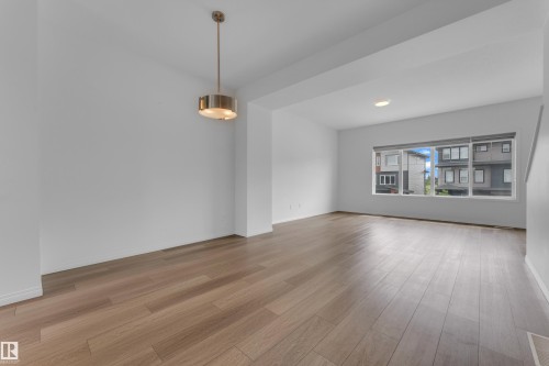 Open-concept living area featuring wood-finish flooring, recessed lighting, and a modern drum pendant light fixture - 1534 157 Street, Edmonton, AB 