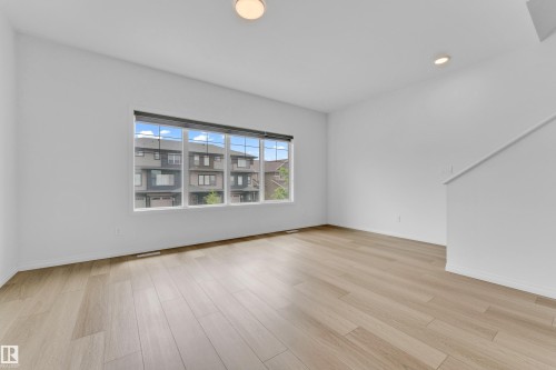 Spacious interior with light-toned wood-finish flooring, white walls, and a large multi-pane window - 1534 157 Street, Edmonton, AB 