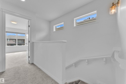 Upper-level landing featuring broadloom carpet, white painted walls, and two horizontal windows - 1534 157 Street, Edmonton, AB 