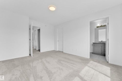 Spacious room featuring light-colored carpeting, a flush-mount ceiling light fixture, and white walls - 1534 157 Street, Edmonton, AB 