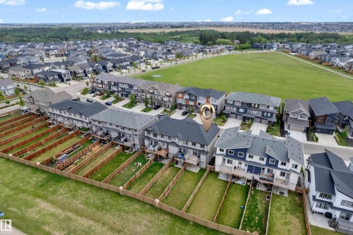 Modern townhome with a dark gray roof and light gray siding, featuring a private fenced backyard with a wooden deck - 1534 157 Street, Edmonton, AB 