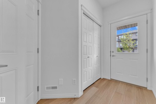 Entryway featuring wood-finish flooring, white trim, and a white paneled door with an integrated window - 1534 157 Street, Edmonton, AB 