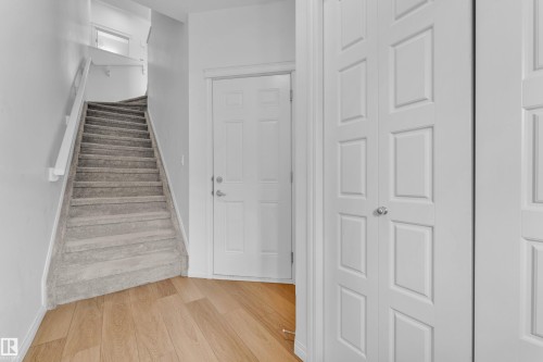 Carpeted staircase with white handrail and light wood-finish flooring - 1534 157 Street, Edmonton, AB 