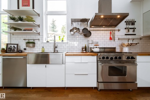 Modern kitchen featuring stainless steel appliances, butcher block countertops, subway tile backsplash, white cabinetry, and wood-finish flooring - 14508 78 Avenue, Edmonton, AB 
