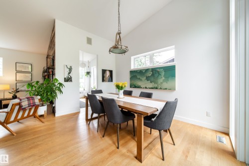 Vaulted ceiling dining area featuring light wood-finish flooring, a contemporary industrial pendant light, and a high horizontal window - 14508 78 Avenue, Edmonton, AB 