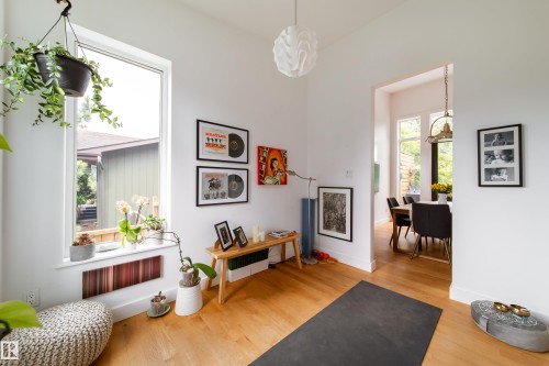 Bright interior space featuring light wood-finish flooring, white walls, and a large window with a built-in baseboard heater - 14508 78 Avenue, Edmonton, AB 