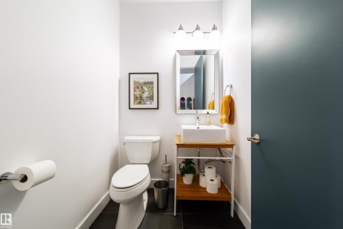 Powder room featuring a vessel sink on a wood-finish vanity with open shelving, a framed mirror, and a three-light vanity fixture - 14508 78 Avenue, Edmonton, AB 