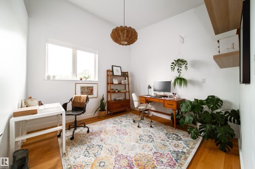 Vaulted ceiling room featuring light wood-finish flooring, a large window, a woven pendant light fixture, and built-in floating shelves - 14508 78 Avenue, Edmonton, AB 