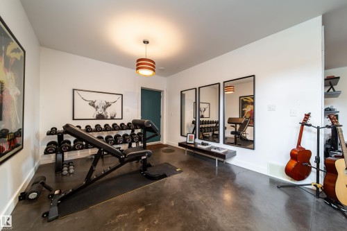 Versatile room featuring polished concrete flooring, white walls, and a contemporary pendant light fixture - 14508 78 Avenue, Edmonton, AB 