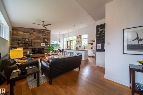 Living area featuring wood-finish flooring and a distinctive wood-paneled accent wall - 14508 78 Avenue, Edmonton, AB 