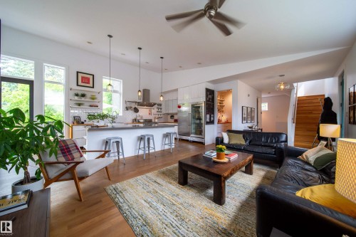 Open-concept living area featuring wood-finish flooring, a contemporary ceiling fan, and abundant natural light from multiple windows - 14508 78 Avenue, Edmonton, AB 